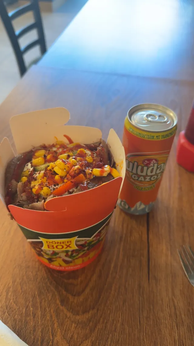 Döner Box mit Fleisch, Mais, Soße und Chiliflocken